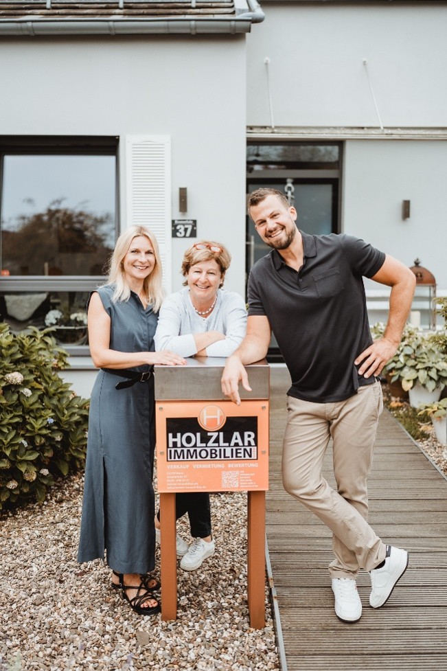 Holzlar-Team mit Verkaufsschild